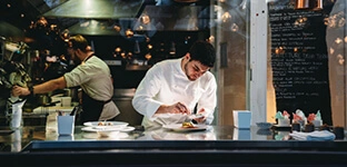Events and Hospitality recruitment: chef preparing a meal in a kitchen.